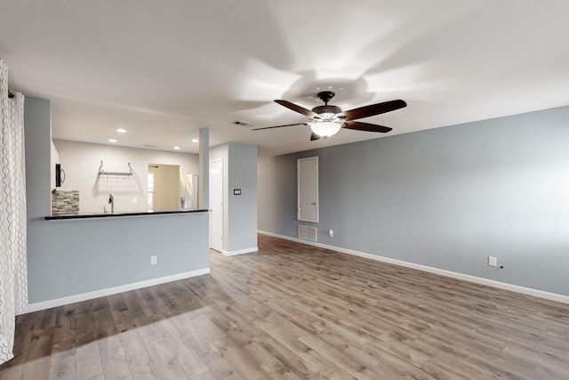 unfurnished room with visible vents, a sink, baseboards, and wood finished floors