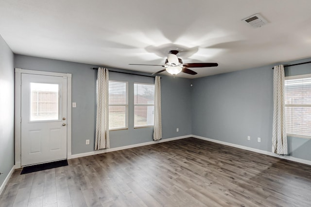 interior space featuring ceiling fan, wood finished floors, visible vents, and baseboards