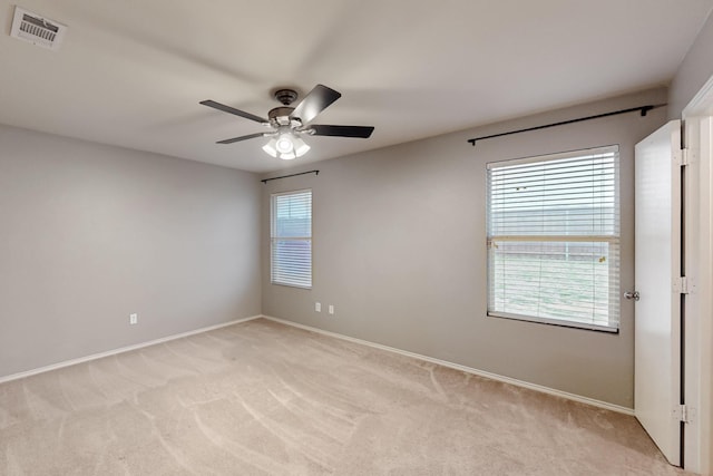 spare room with baseboards, a ceiling fan, visible vents, and light colored carpet