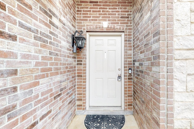 doorway to property featuring brick siding