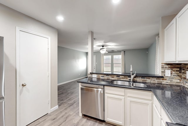 kitchen featuring tasteful backsplash, light wood-type flooring, dishwasher, and a sink