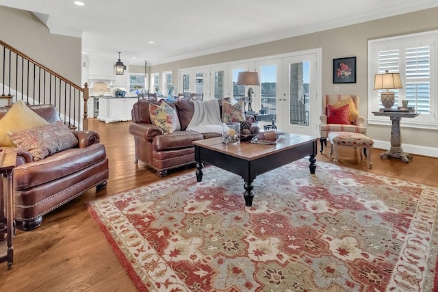 living room featuring light wood-type flooring, stairway, ornamental molding, and french doors