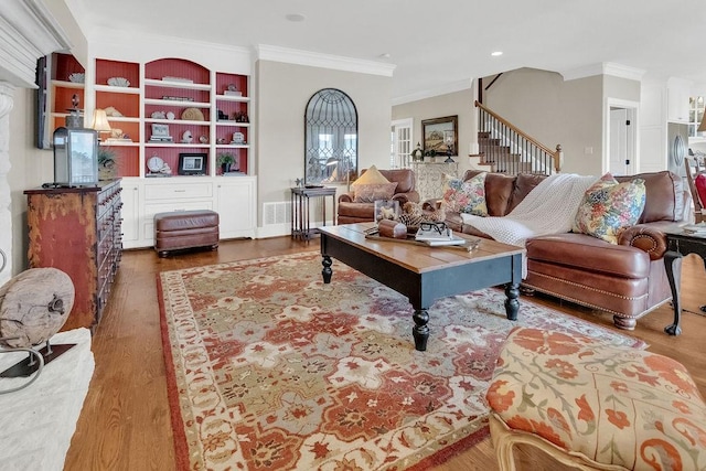 living room featuring built in features, crown molding, stairway, and wood finished floors