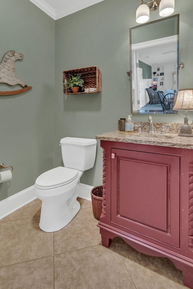 bathroom with toilet, vanity, baseboards, tile patterned floors, and crown molding