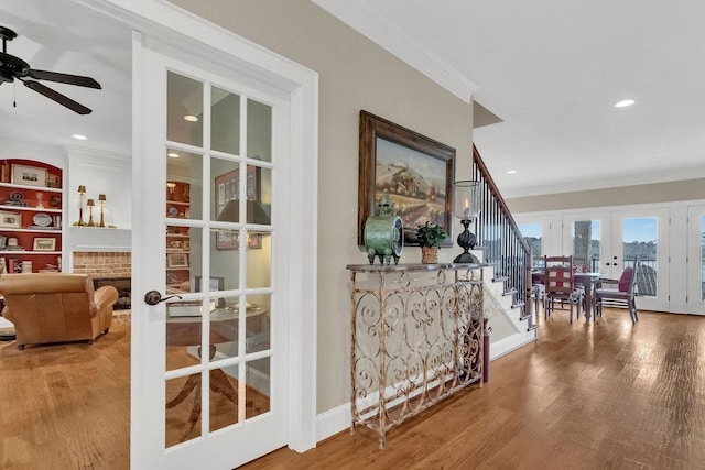 hall with recessed lighting, wood finished floors, ornamental molding, french doors, and stairway