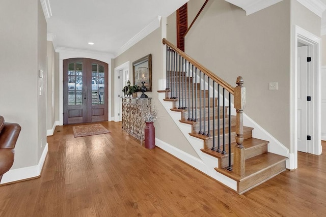 entryway with crown molding, arched walkways, wood finished floors, and french doors