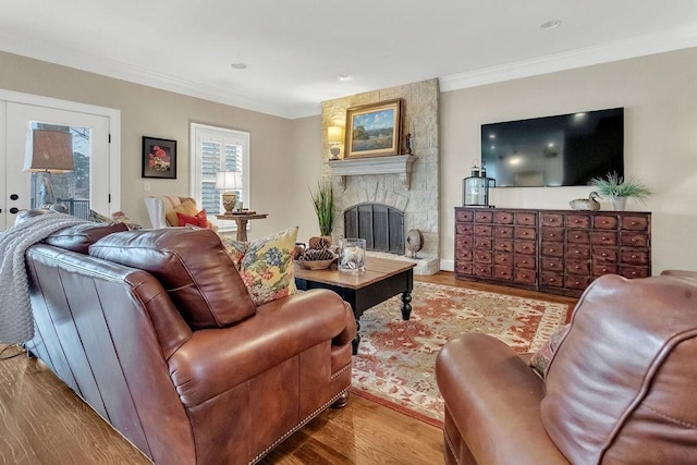 living area with crown molding, a fireplace, and wood finished floors