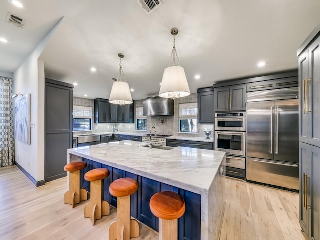 kitchen with light wood-type flooring, visible vents, a center island with sink, and appliances with stainless steel finishes