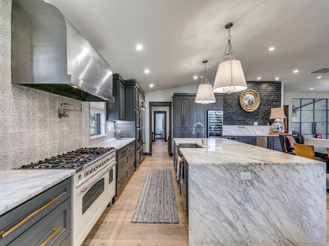 kitchen with range with gas stovetop, light stone counters, island exhaust hood, tasteful backsplash, and lofted ceiling