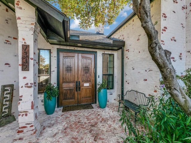 doorway to property featuring a shingled roof and stucco siding