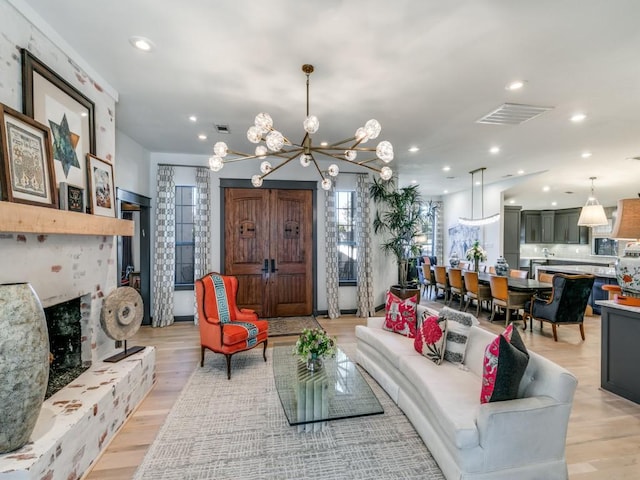 living room with light wood-style flooring, visible vents, a fireplace with raised hearth, and recessed lighting