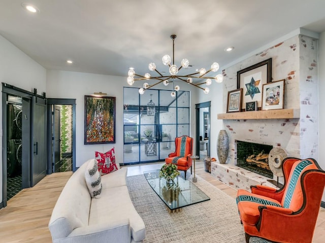 living room featuring a barn door, a fireplace, wood finished floors, and recessed lighting