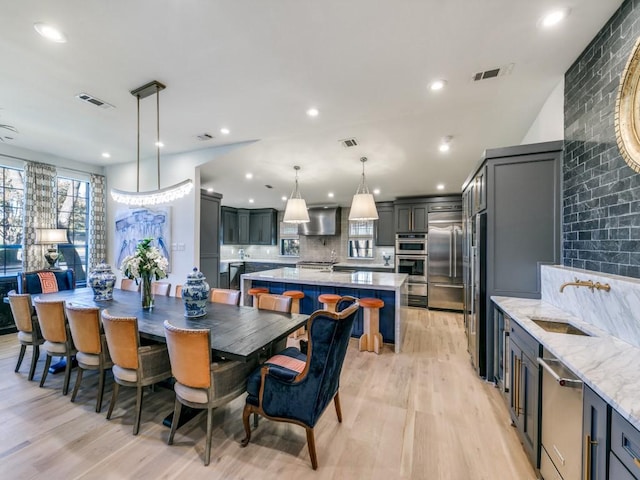 dining area with light wood-type flooring, visible vents, and recessed lighting