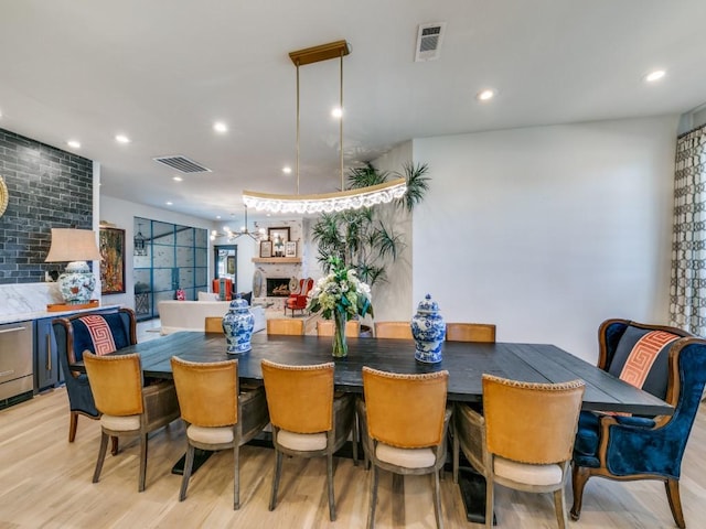 dining room with light wood-style floors, a fireplace, visible vents, and recessed lighting