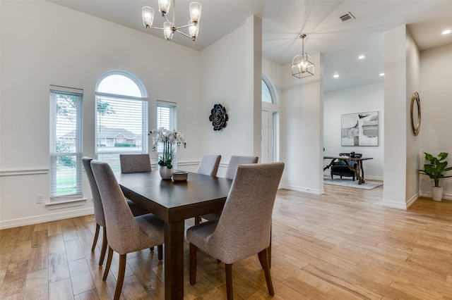 dining room with light wood-style floors, visible vents, and a notable chandelier