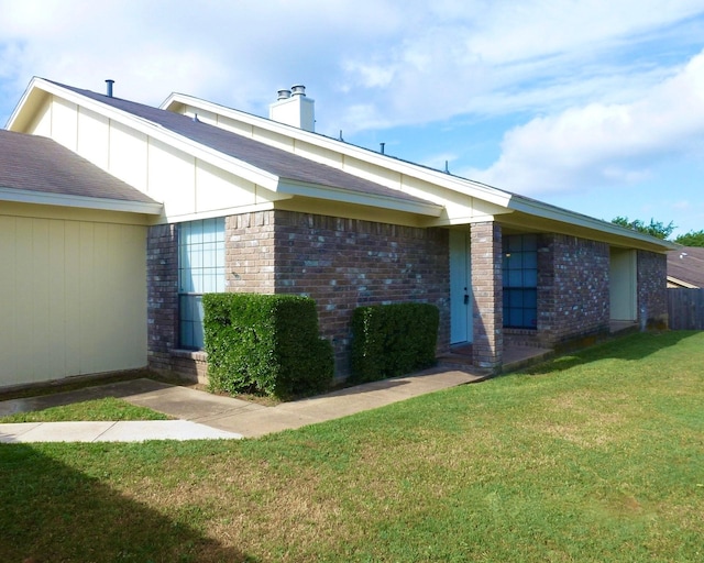 back of house featuring a yard, brick siding, and a chimney