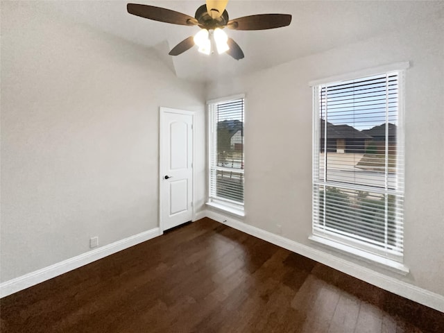 empty room with dark wood-type flooring, baseboards, and a ceiling fan