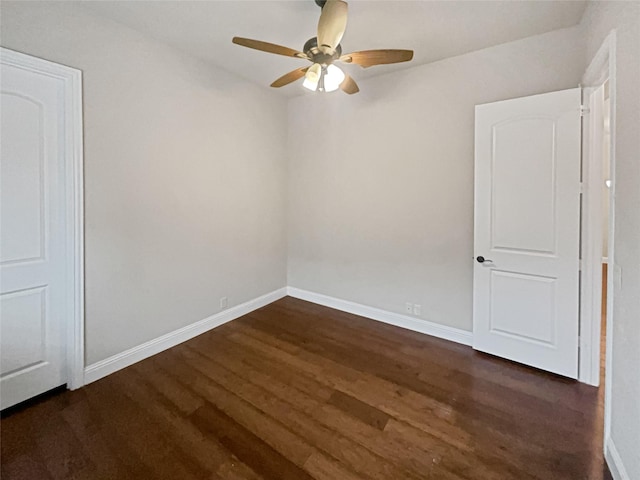 unfurnished room with dark wood-style flooring, a ceiling fan, and baseboards