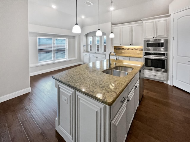 kitchen with stainless steel appliances, dark wood-style flooring, a sink, and decorative backsplash