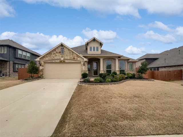 view of front of property featuring driveway, stone siding, an attached garage, and fence