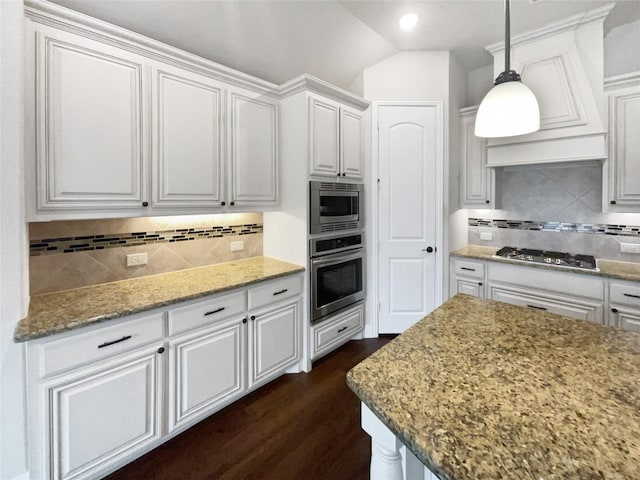 kitchen featuring lofted ceiling, light stone counters, stainless steel appliances, white cabinetry, and pendant lighting