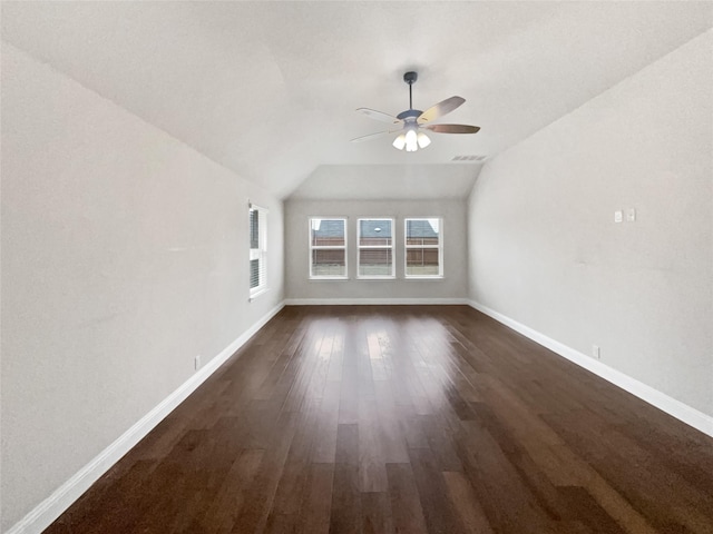 interior space featuring a ceiling fan, vaulted ceiling, dark wood finished floors, and baseboards