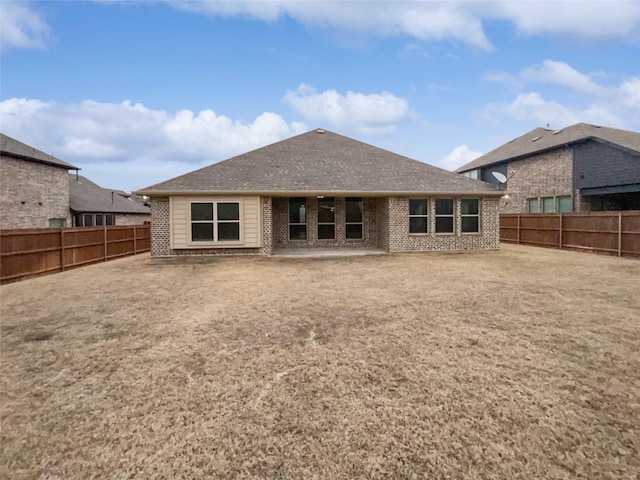 back of house with a fenced backyard, a shingled roof, and brick siding