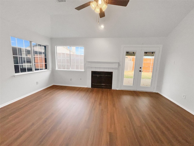 unfurnished living room with french doors, a tiled fireplace, baseboards, and wood finished floors