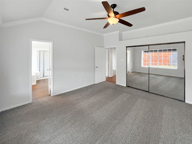 unfurnished bedroom featuring visible vents, baseboards, carpet, vaulted ceiling, and crown molding