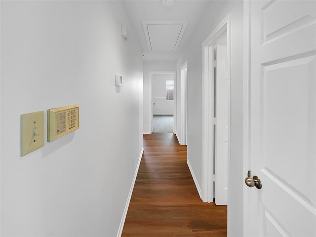 hall featuring attic access, baseboards, and wood finished floors