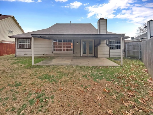 back of house with a fenced backyard, french doors, a lawn, a chimney, and a patio area