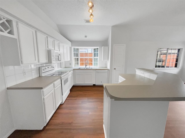 kitchen with white appliances, a sink, white cabinets, backsplash, and dark wood finished floors