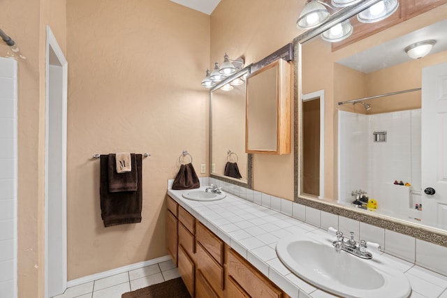 full bath with double vanity, a sink, baseboards, and tile patterned floors