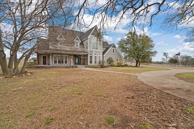 view of front of house with covered porch, fence, and a front yard