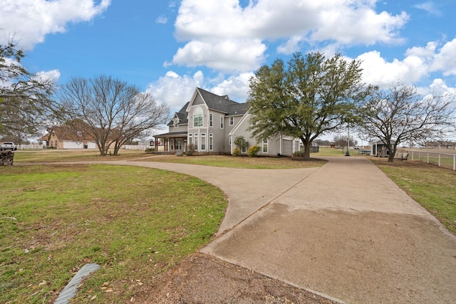 view of side of property featuring a lawn, driveway, and fence