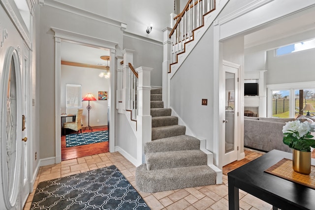 entryway featuring stairs, a high ceiling, baseboards, and stone tile floors