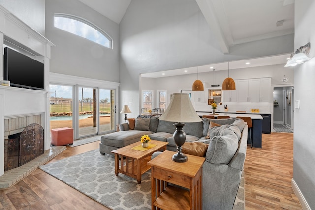 living area with recessed lighting, light wood-style floors, a brick fireplace, high vaulted ceiling, and baseboards