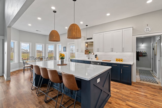 kitchen with light wood-style floors, a center island, a breakfast bar area, and tasteful backsplash