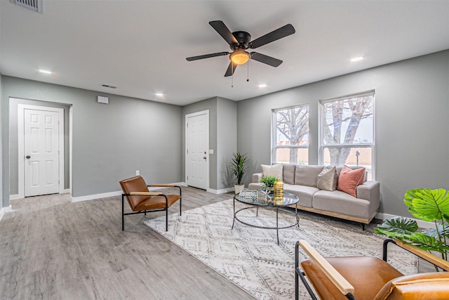 living area with a ceiling fan, light wood-type flooring, visible vents, and baseboards