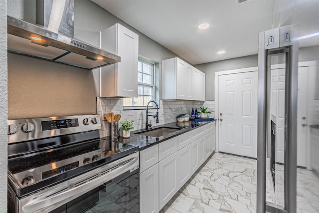 kitchen with marble finish floor, electric range, decorative backsplash, a sink, and wall chimney exhaust hood