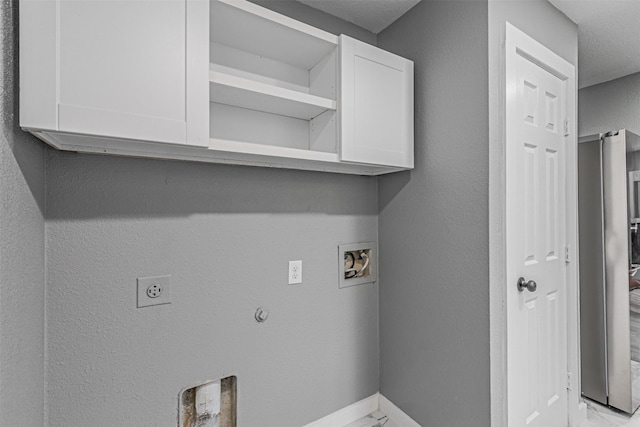 clothes washing area with cabinet space, baseboards, a textured wall, washer hookup, and electric dryer hookup