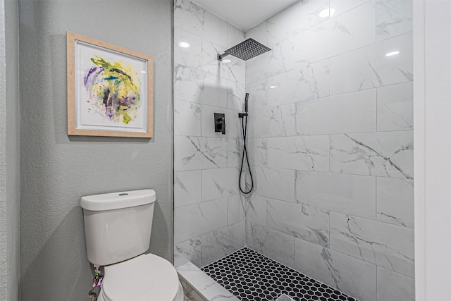 full bathroom featuring a textured wall, a tile shower, and toilet