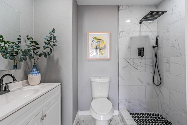 full bath with marble finish floor, a tile shower, vanity, and toilet