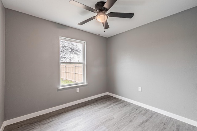 empty room with ceiling fan, wood finished floors, and baseboards