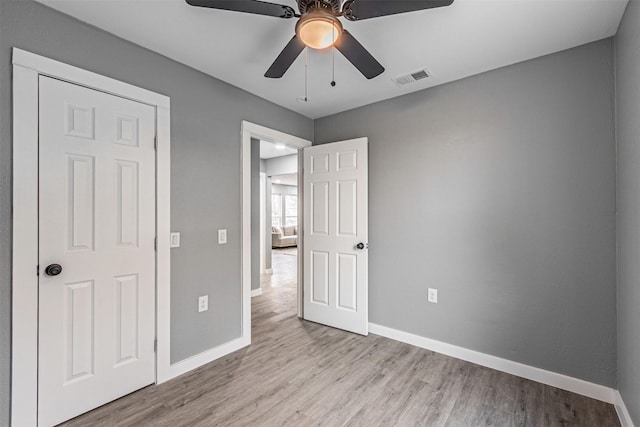 unfurnished bedroom with a ceiling fan, visible vents, baseboards, and wood finished floors