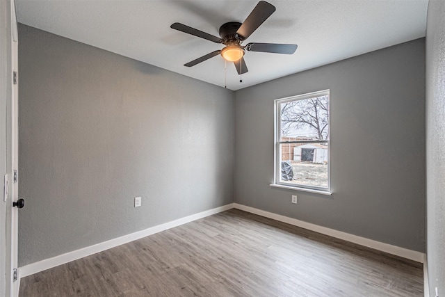 unfurnished room with ceiling fan, wood finished floors, and baseboards