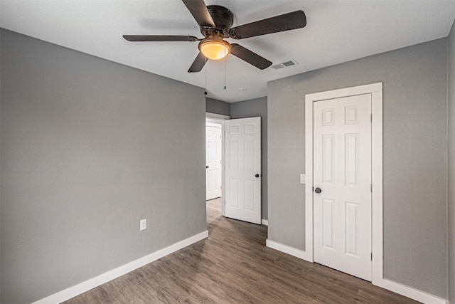 unfurnished bedroom featuring a ceiling fan, baseboards, visible vents, and wood finished floors