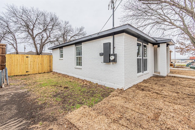 view of side of home with brick siding and fence