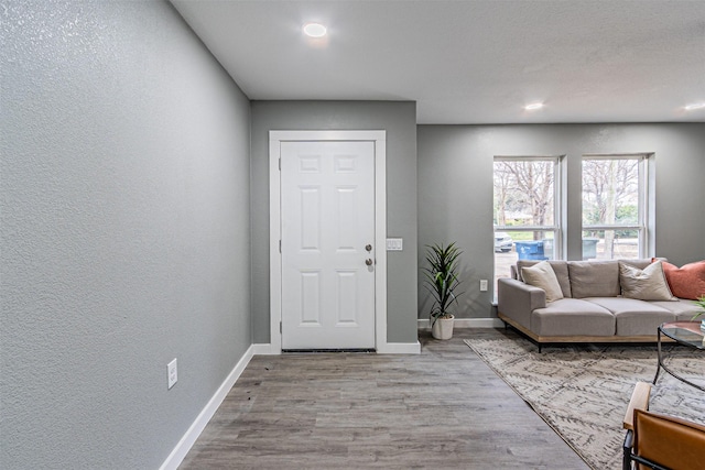 entrance foyer featuring a textured wall, baseboards, and wood finished floors