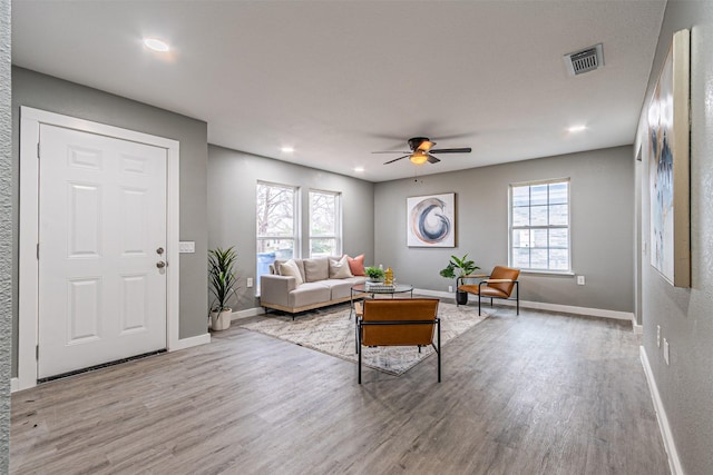 living room featuring baseboards, visible vents, ceiling fan, and wood finished floors